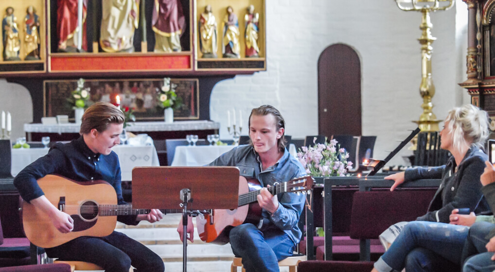 To drenge spiller på guitar i kirke